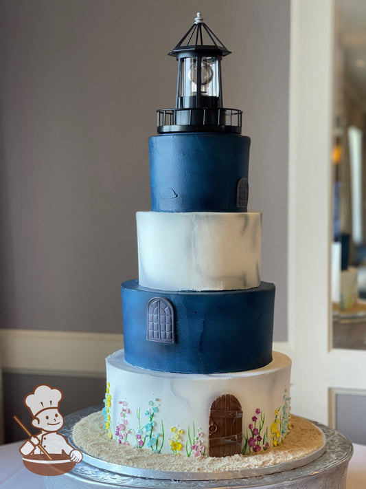 4-tier cake decorated to look like a light house with white and blue icing, fondant doors and windows and small sugar flowers at the base.