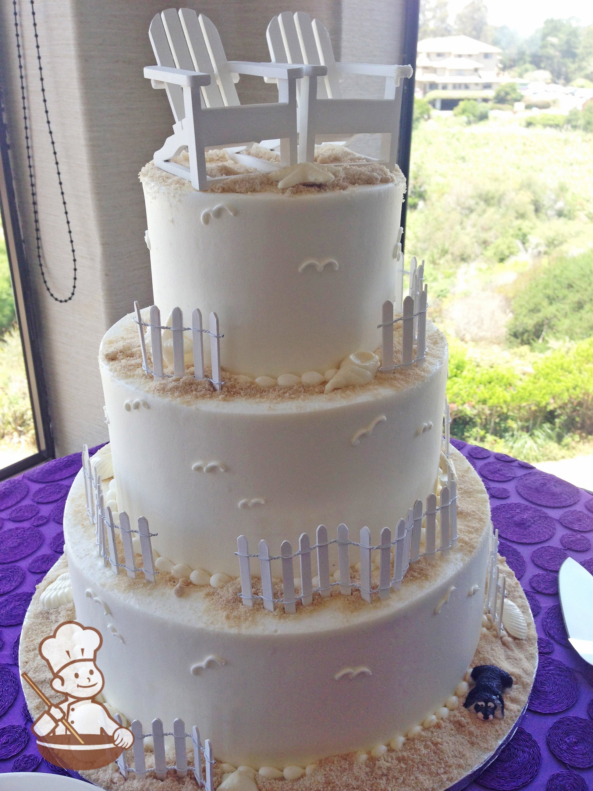 3-tier cake with smooth white icing and decorated with wood white fences, 2 white wood beach chairs, white chocolate seashells and sugar "sand".
