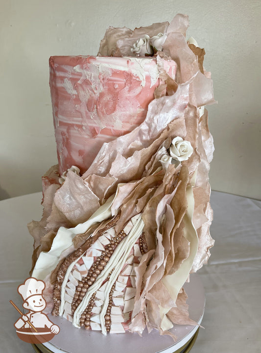 2-tier pink and white cake in textured patterns with cascading ruffles and beads. Small white sugar flowers in the mauve and cream ruffles.