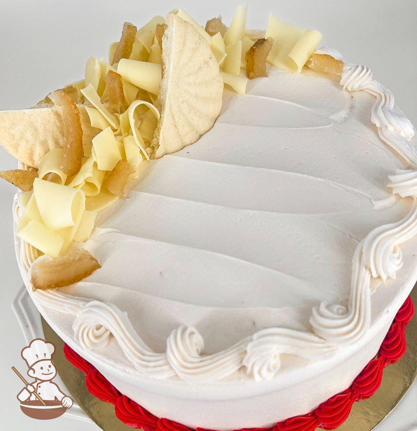 Round cake with white icing, white chocolate curls, shortbread cookie pieces, and dried lemon on top. Red buttercream border at the base.