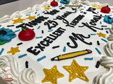 Sheet cake with white buttercream frosting, decorated with red apple designs, blue flowers, yellow stars, a yellow pencil, and blue and black sprinkles.