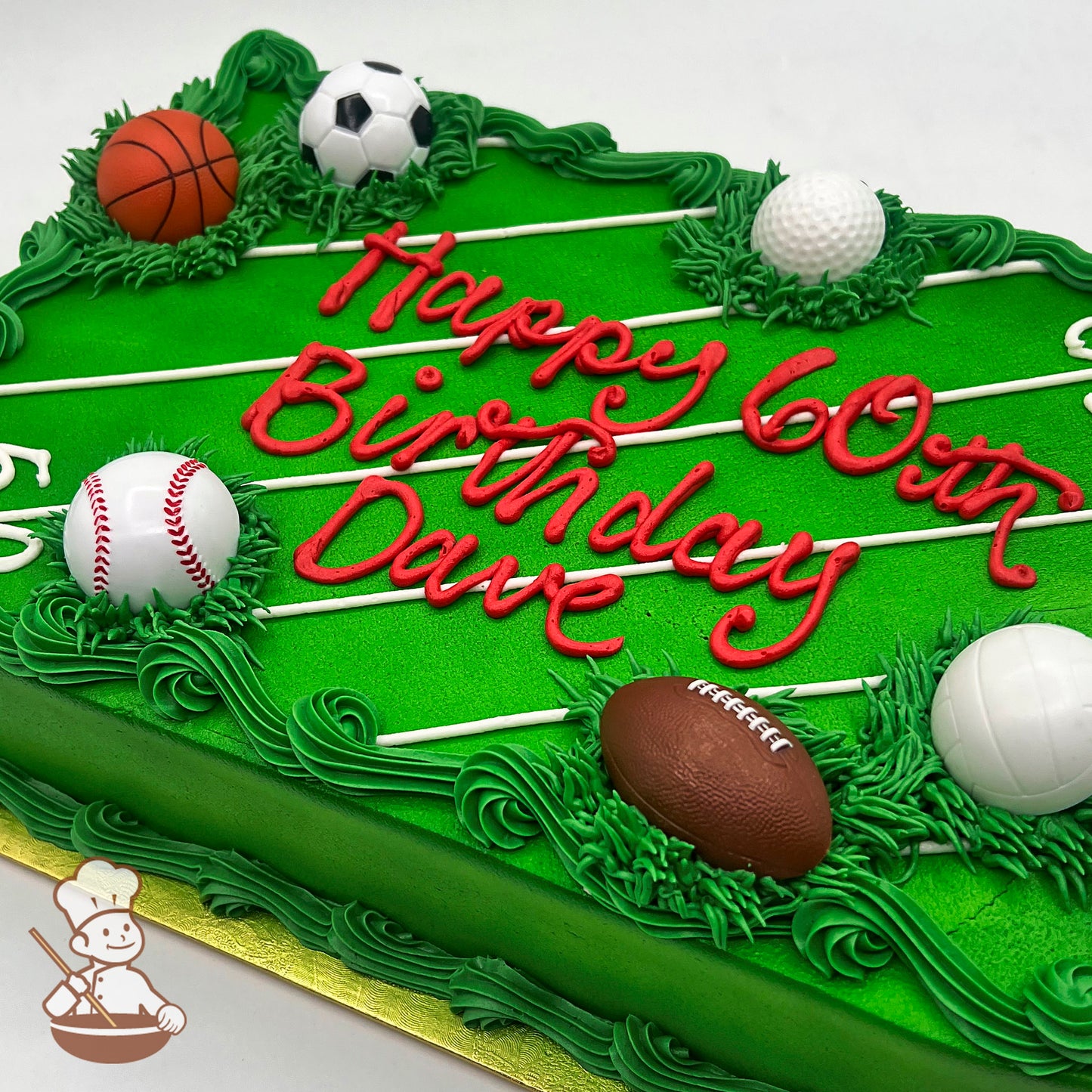 Green sheet cake decorated with buttercream grass, white lines resembling a sports field, and plastic toy balls for baseball, basketball, soccer, football, and golf.