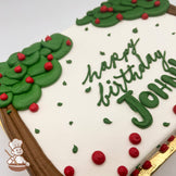 Sheet cake with buttercream apple tree decorations, featuring green leaves, red apples, and brown tree trunks. Red and green accents scattered on white frosting.