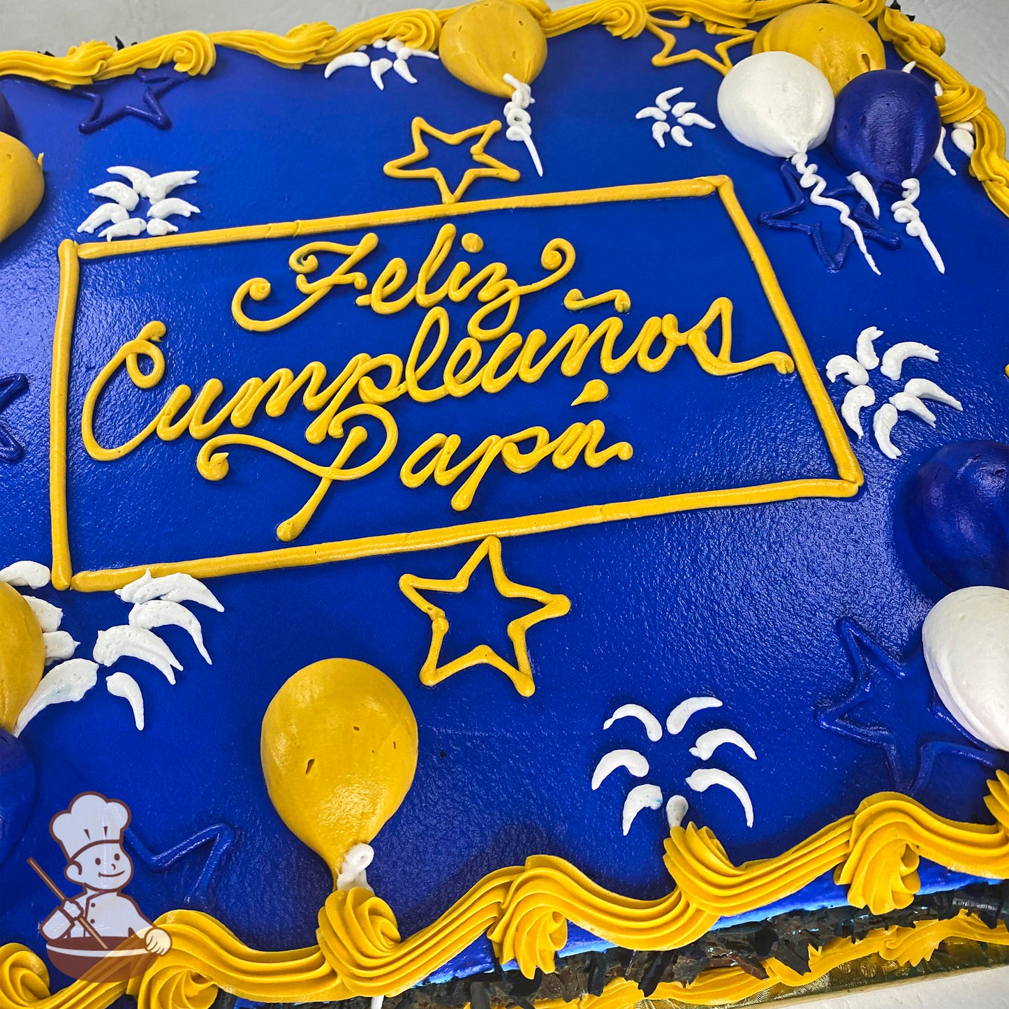 Blue sheet cake with yellow and white buttercream balloons, stars, and fireworks decorations. White and blue accents.