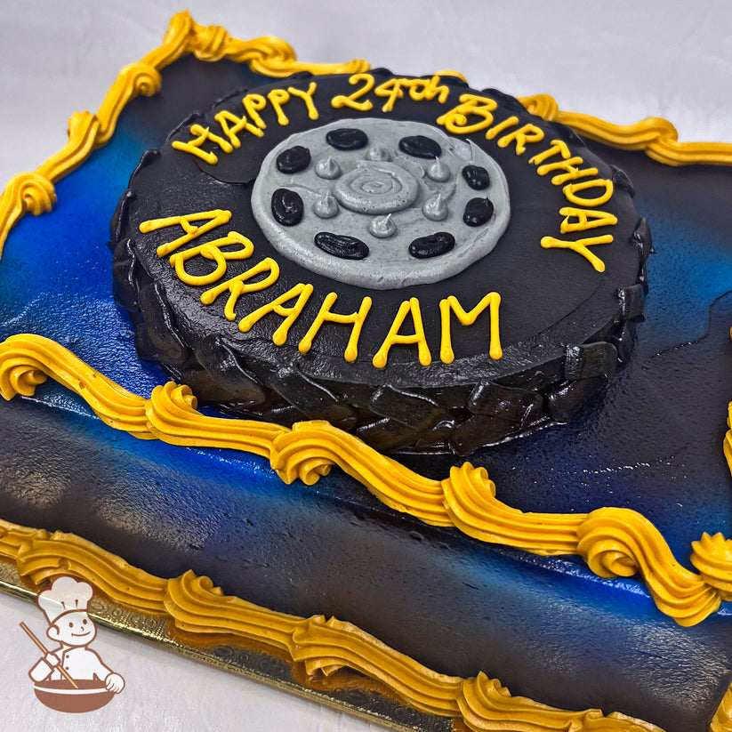 Sheet cake with a black tire-shaped buttercream decoration, silver hubcap details, yellow piped borders, and a blue-to-black gradient background.