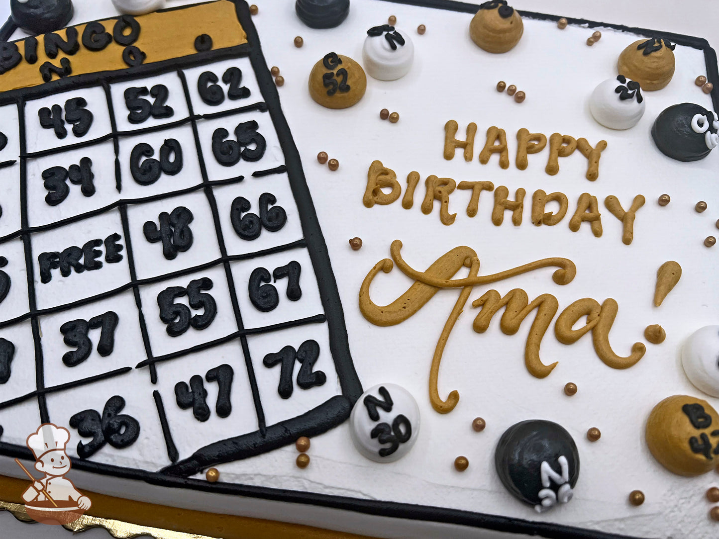 Sheet cake with buttercream bingo card and balls, decorated in black, white, and gold. Gold, black and white buttercream dots scattered around.