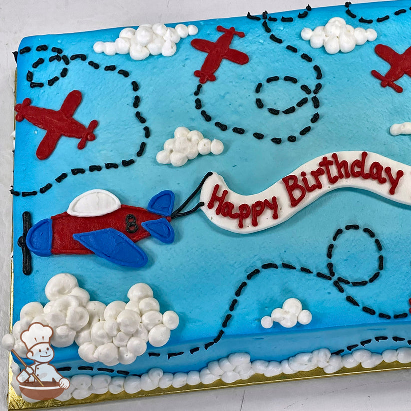 Sheet cake with blue background, red and blue biplane, black dotted flight trails, white buttercream clouds, and a banner decoration.