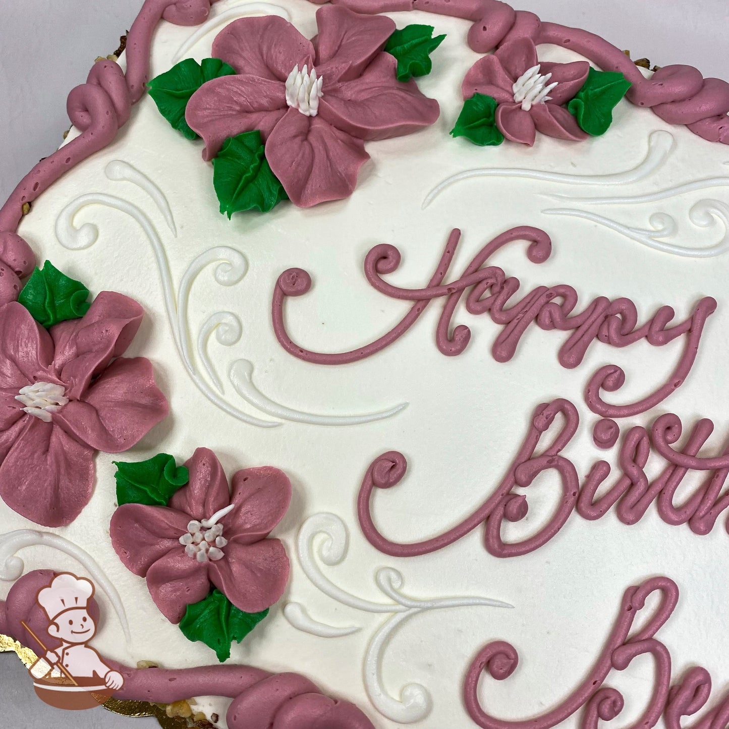 Sheet cake with pink buttercream flowers, green leaves, and elegant white scrolls.