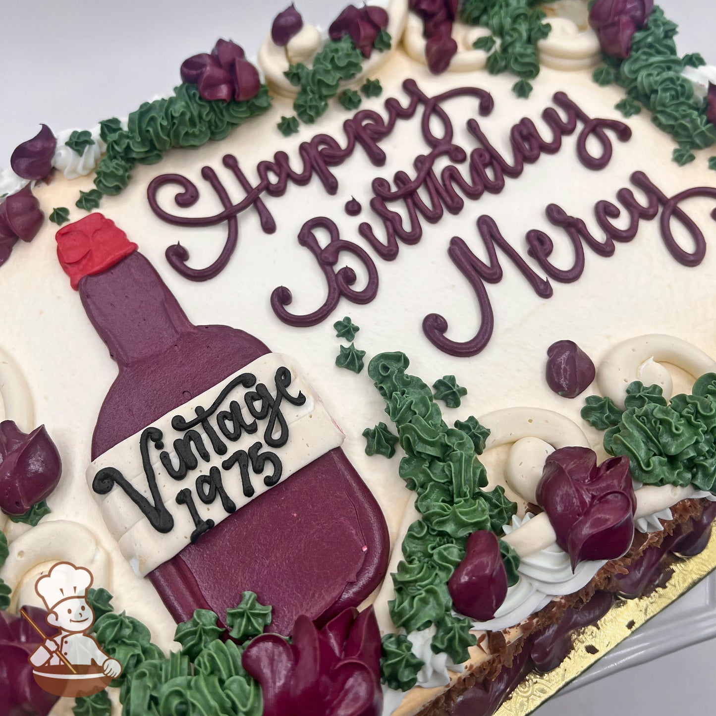 Sheet cake with buttercream decorations featuring a purple wine bottle and green vines.
