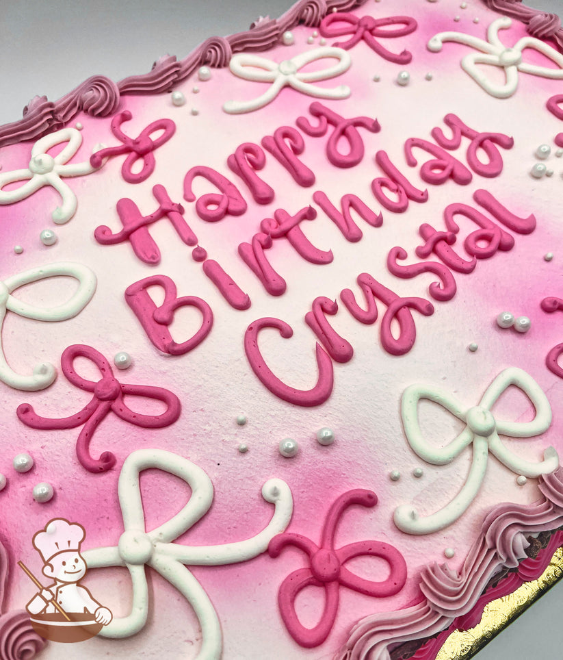 Sheet cake with pink and white buttercream bows, sugar pearls, and a pink and white ombre spray design, bordered by pink piped frosting.