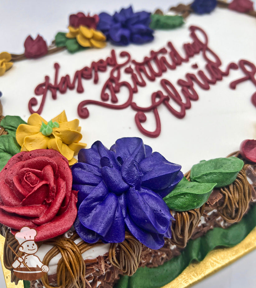 Sheet cake with buttercream decorations featuring a branch border with assorted florals: red roses, blue flowers, yellow flowers, and green leaves.
