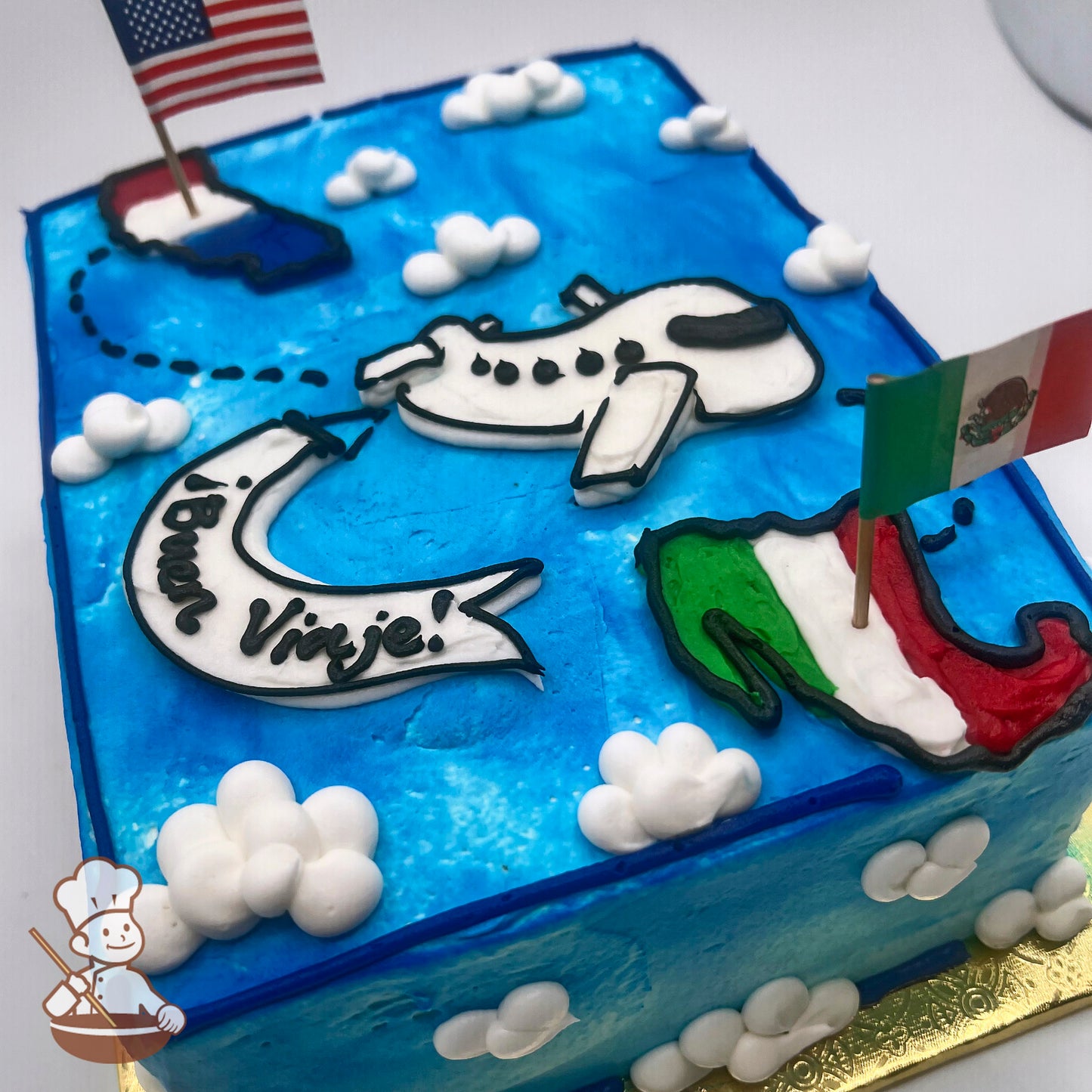 Sheet cake with blue frosting, decorated with a white airplane, clouds, U.S. and Mexican flags, and map outlines of the U.S. and Mexico.