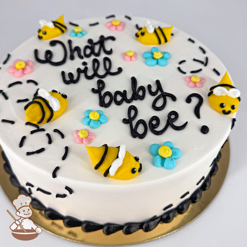 Round white cake decorated with yellow buttercream bumble bees, pastel daisies in pink and blue, and black dotted trails. Black frosting border on the base.