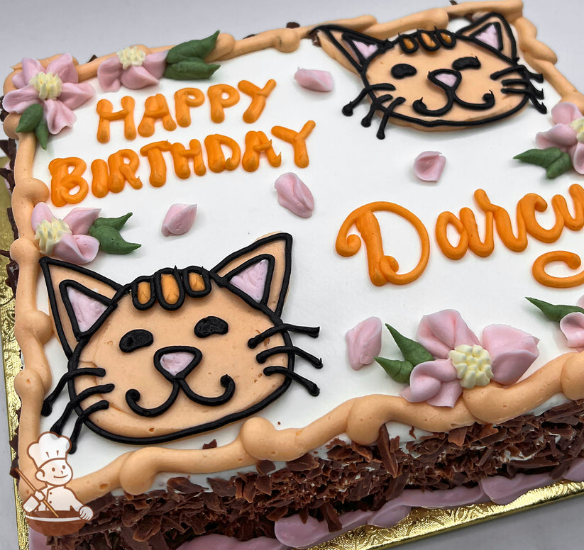 Sheet cake with buttercream cat faces, pink flowers and green leaves.