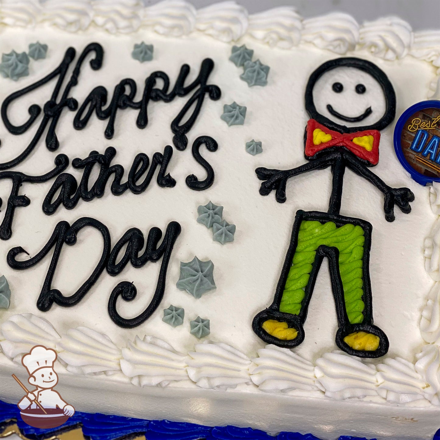 Sheet cake with white icing, a stick figure man in green pants, red bow tie, and yellow shoes, surrounded by gray star decorations.