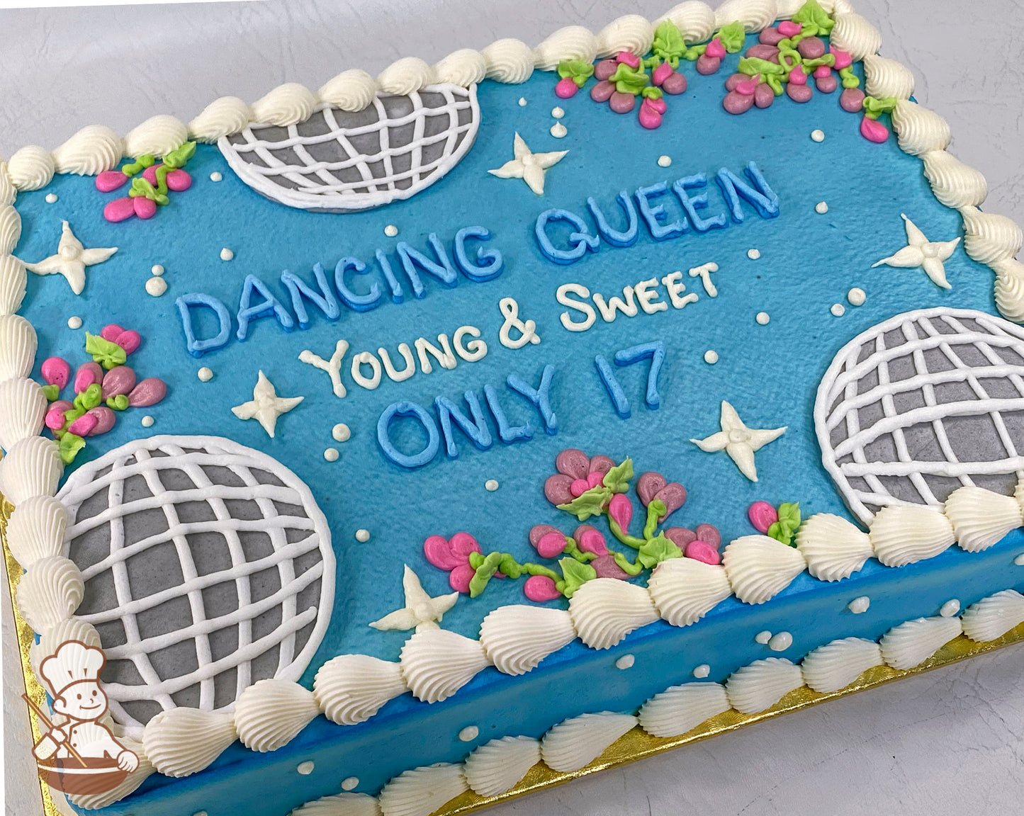 Blue sheet cake with buttercream disco balls, white stars, mini pink flowers, and a white piped border.
