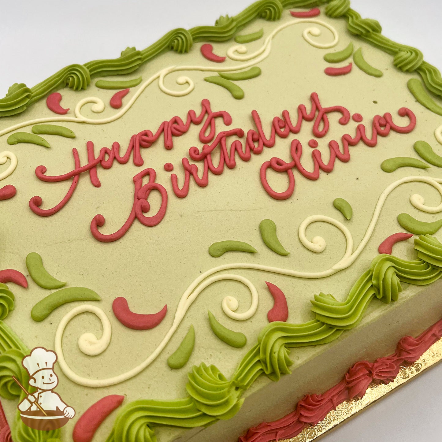 Sheet cake with light green frosting, decorated with pink and white scrolls, green and pink piped accents, and green piped borders.