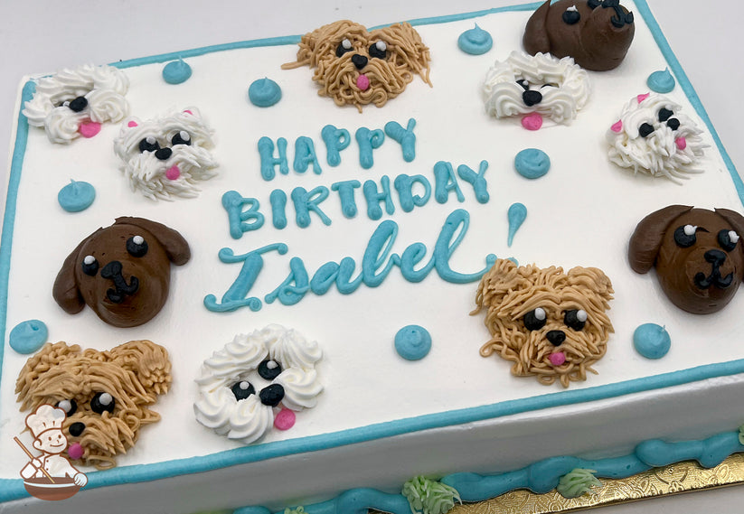 Sheet cake with buttercream dog faces, including brown and white dogs, and blue dots. Blue and green piping decorates the borders.
