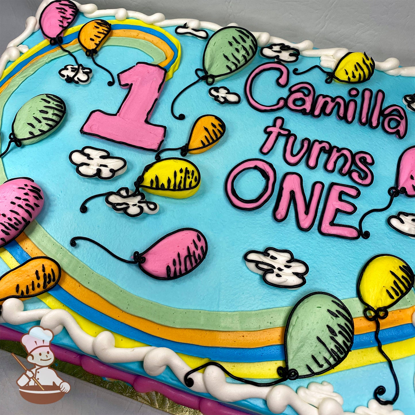 A sheet cake with a blue base, decorated with hand-piped balloons in pink, yellow, orange, and green, white clouds, and a colorful rainbow.