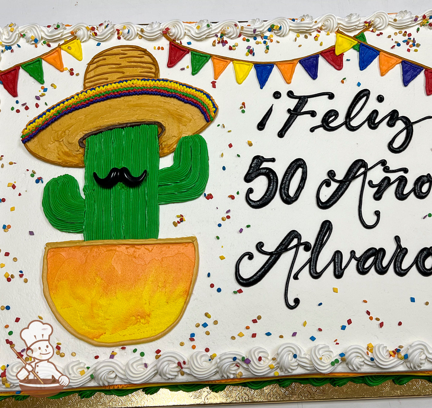 Sheet cake with buttercream decorations, featuring a hand-piped cactus in a sombrero and pot, colorful banner, confetti sprinkles, and piped white border.
