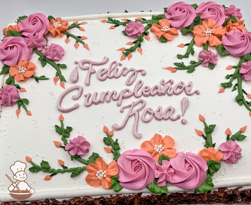 Sheet cake with white frosting, decorated with hand-piped pink rosettes, orange flowers, green vines, and leaves.