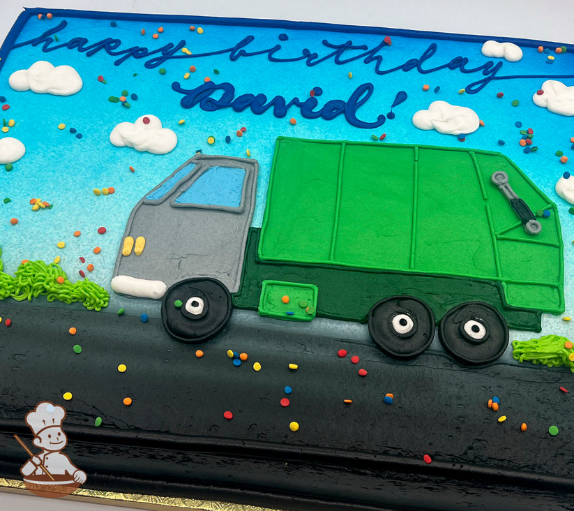 Sheet cake with icing decorations of a green garbage truck on a black road, blue sky, white clouds, and colorful sprinkles scattered throughout.