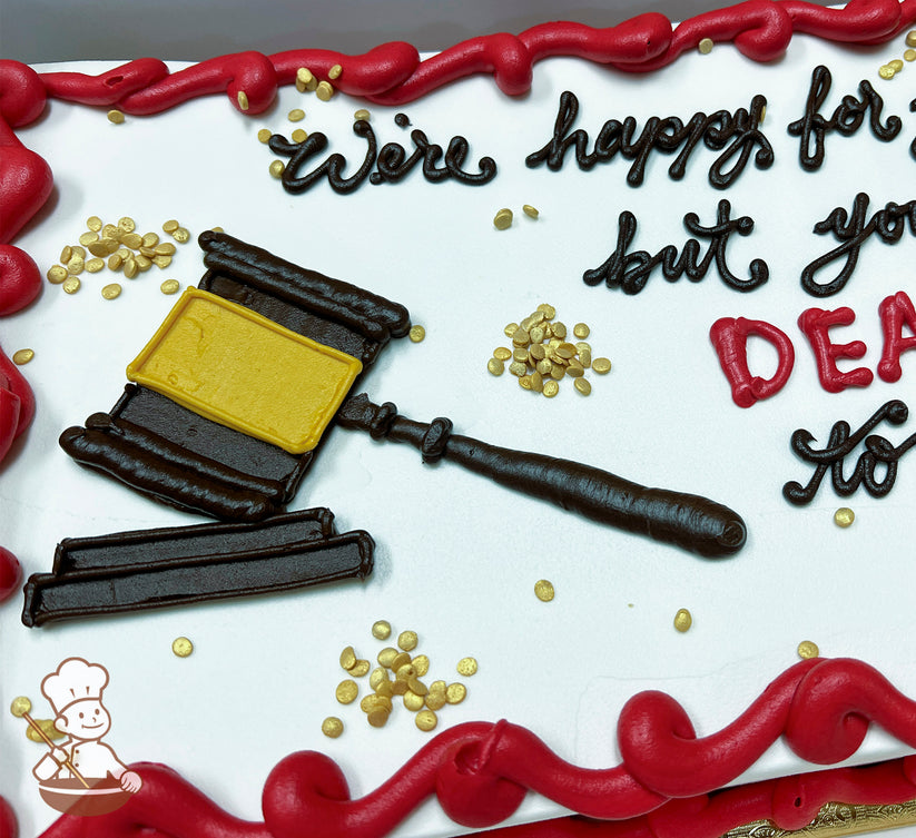 Sheet cake with white frosting, red buttercream border, and a dark brown and yellow buttercream gavel decoration. Gold sprinkles scattered on top.