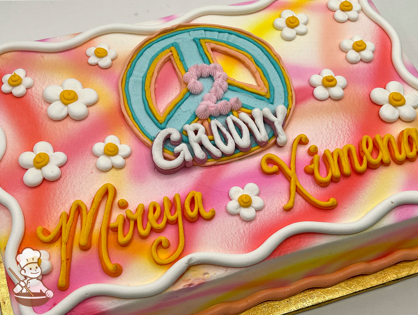 Colorful sheet cake with buttercream daisies, a large peace sign, and vibrant spray.