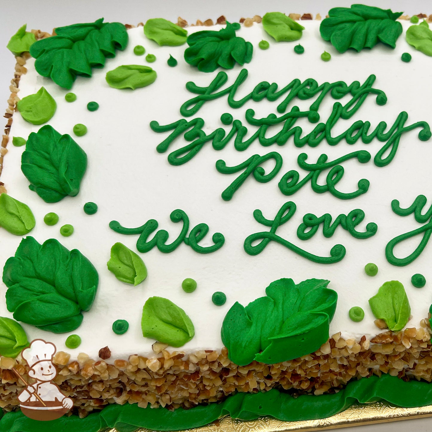 Sheet cake with white frosting, decorated with green buttercream leaves and small green dots.