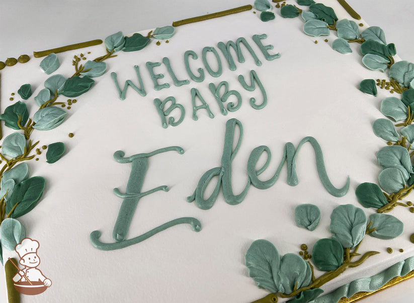 Sheet cake with white frosting, decorated with green buttercream eucalyptus leaves, golden branches, and a piped message in green icing.