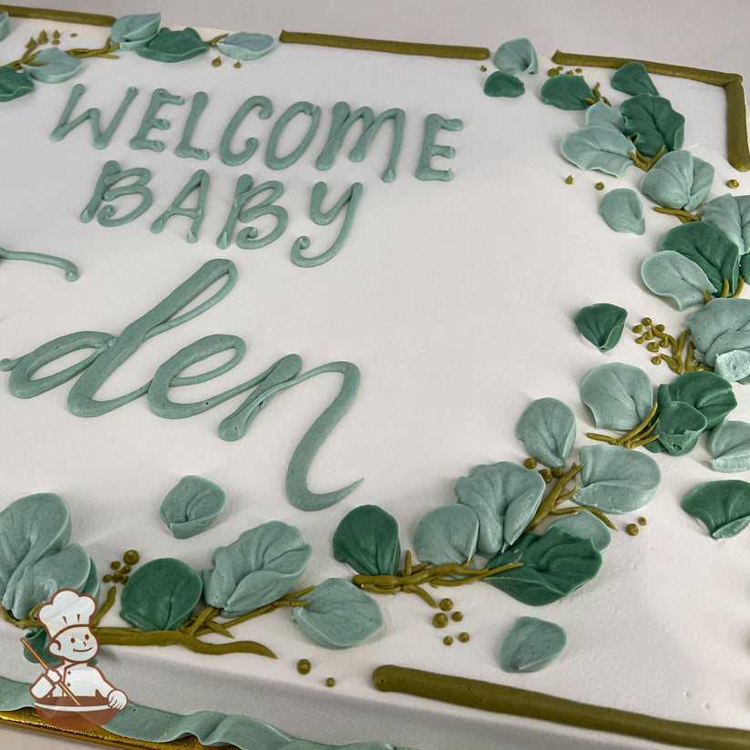 Sheet cake with white frosting, decorated with green buttercream eucalyptus leaves, golden branches, and a piped message in green icing.