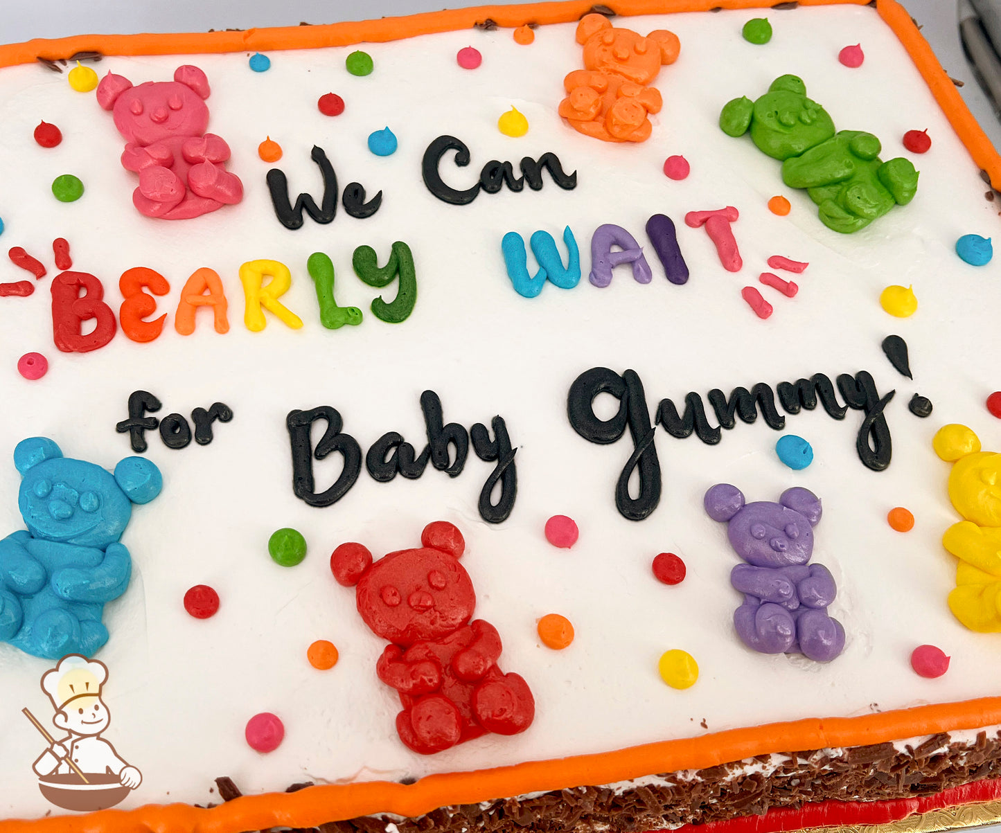 Sheet cake with colorful buttercream gummy bears and dots. Bears in pink, orange, green, blue, red, purple, and yellow. Orange border.