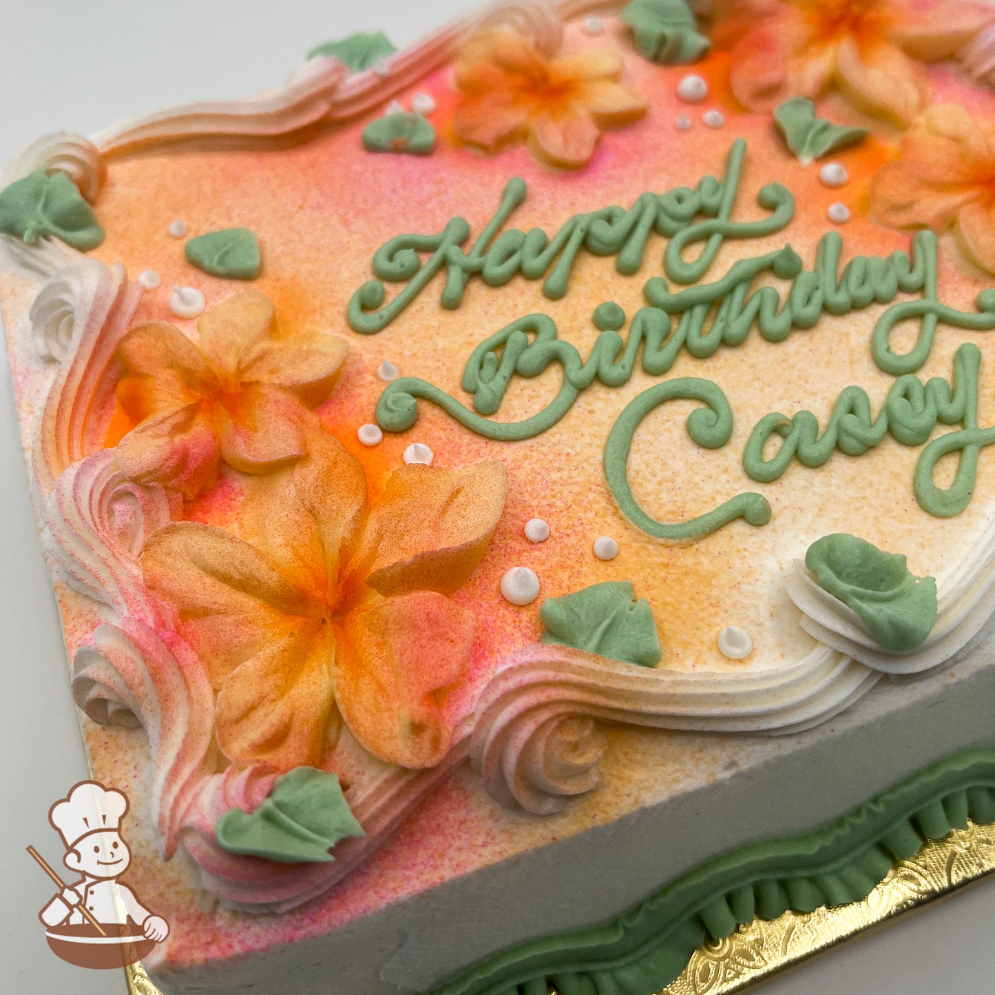 Sheet cake with orange and pink airbrushed flowers, decorated with plumeria flowers, green leaves, white dots, and piped swirl trims.