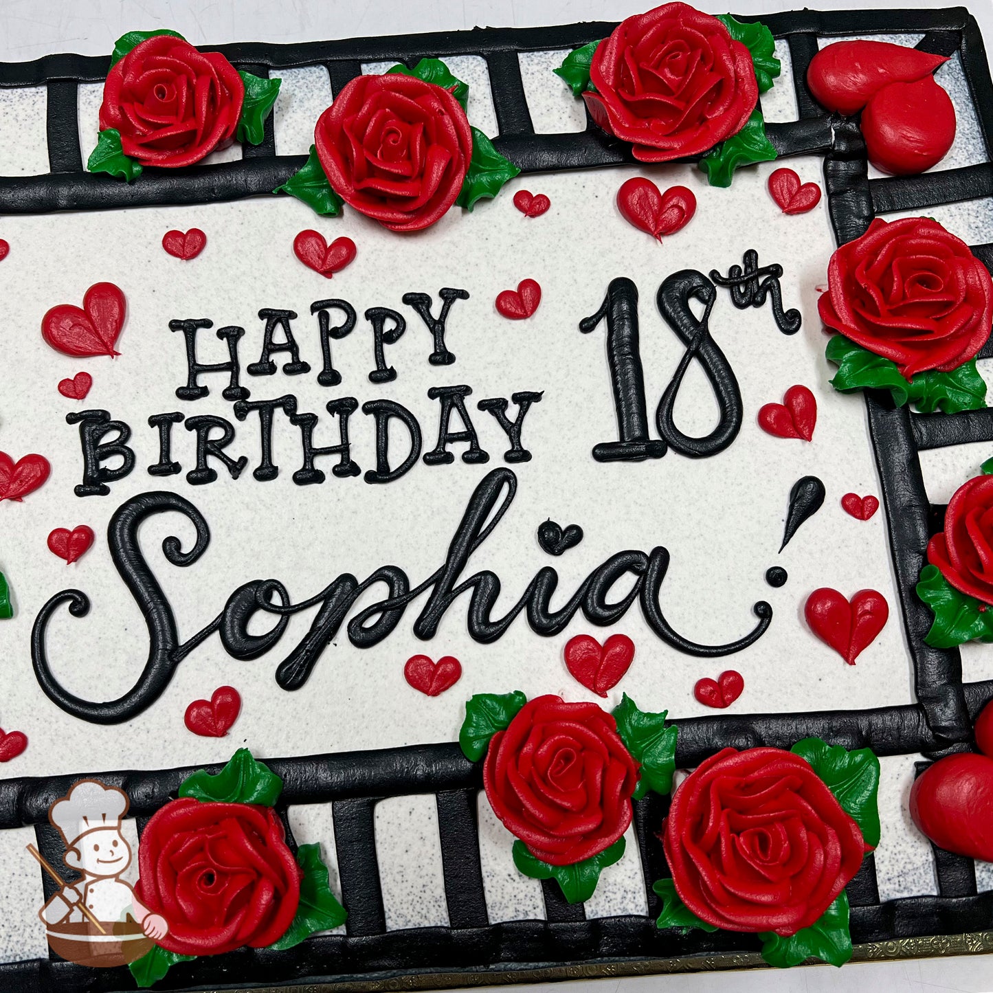 Sheet cake with buttercream decorations, featuring red roses with green leaves, small red hearts, and a black striped border design.