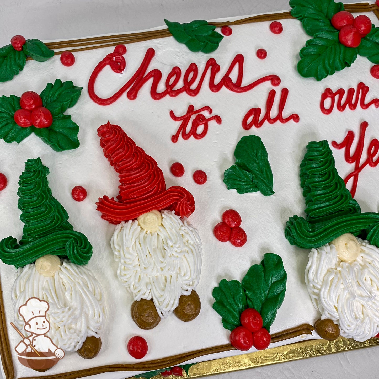 Sheet cake with buttercream holiday gnomes in red and green hats, white beards, and brown shoes, surrounded by holly leaves and red berries.