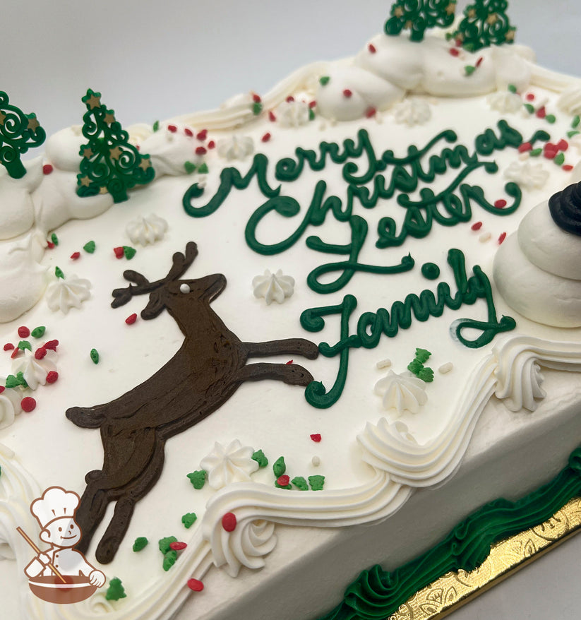 Sheet cake with buttercream snowmen, reindeer, and green plastic tree decorations. Snow-like icing and colorful sprinkles adorn the top.