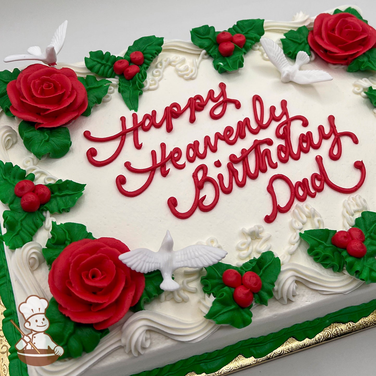 Sheet cake with white frosting, decorated with red buttercream roses, green leaves, red berries, and white plastic doves.