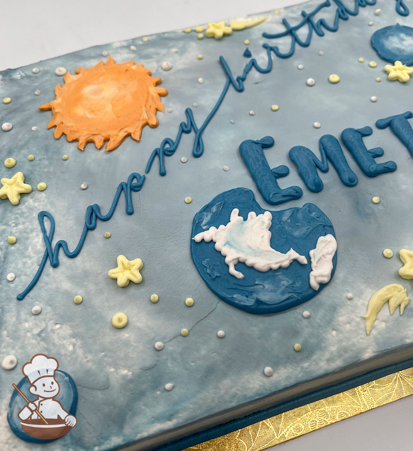Sheet cake with colored icing, decorated with a sun, planets, stars, and a ringed planet. White and yellow dots resemble stars.