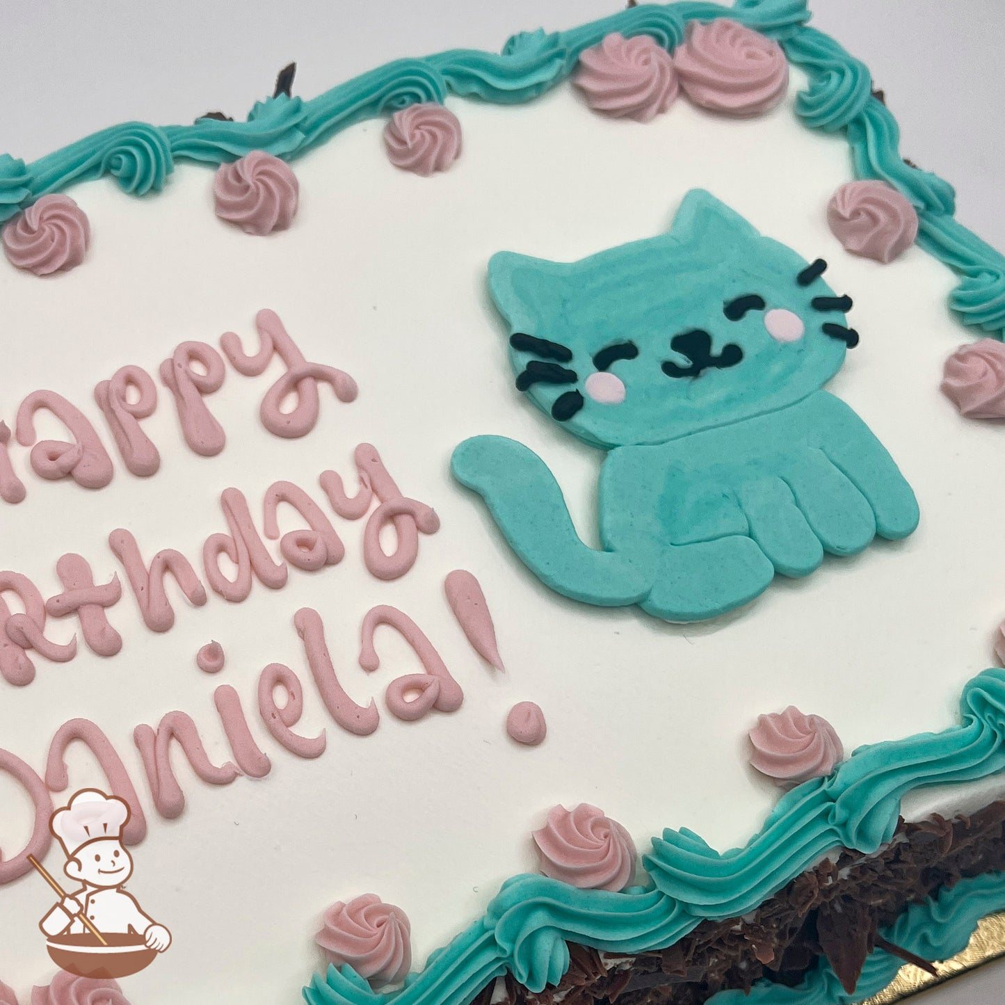 A sheet cake with white frosting, decorated with a teal buttercream cat, pink rosettes, and teal swirl trims along the border.