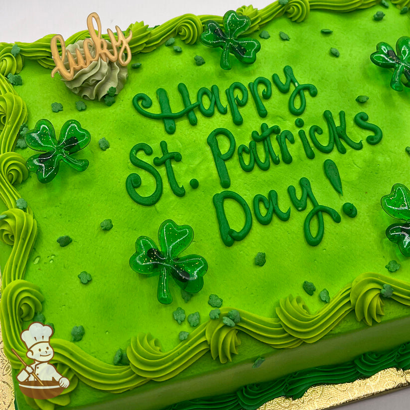 Green sheet cake with buttercream swirl trims, plastic shamrock rings, and shamrock sprinkles.