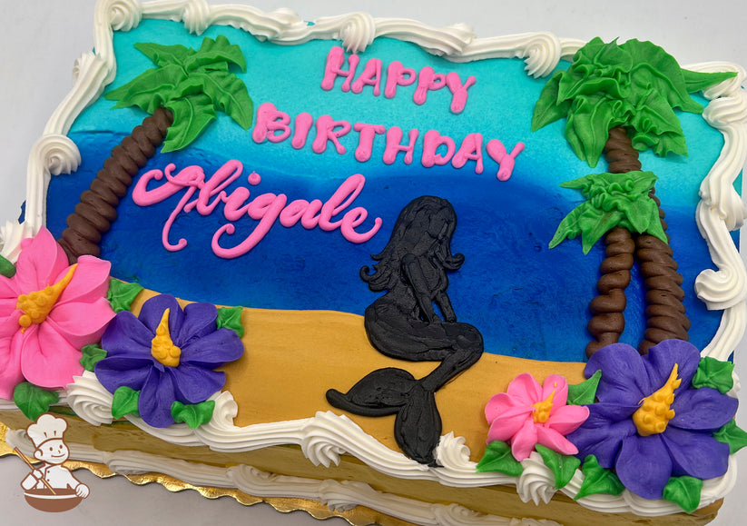 Sheet cake with buttercream decorations featuring a black mermaid silhouette on a sandy beach, blue ocean, palm trees, and pink and purple flowers.