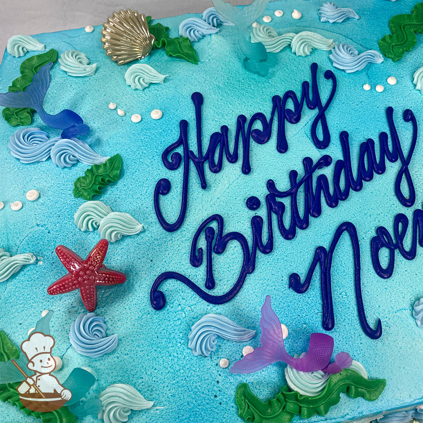 Blue sheet cake with buttercream waves, seaweed, and white bubbles. Decorated with plastic mermaid tails, a red starfish, and a gold seashell.