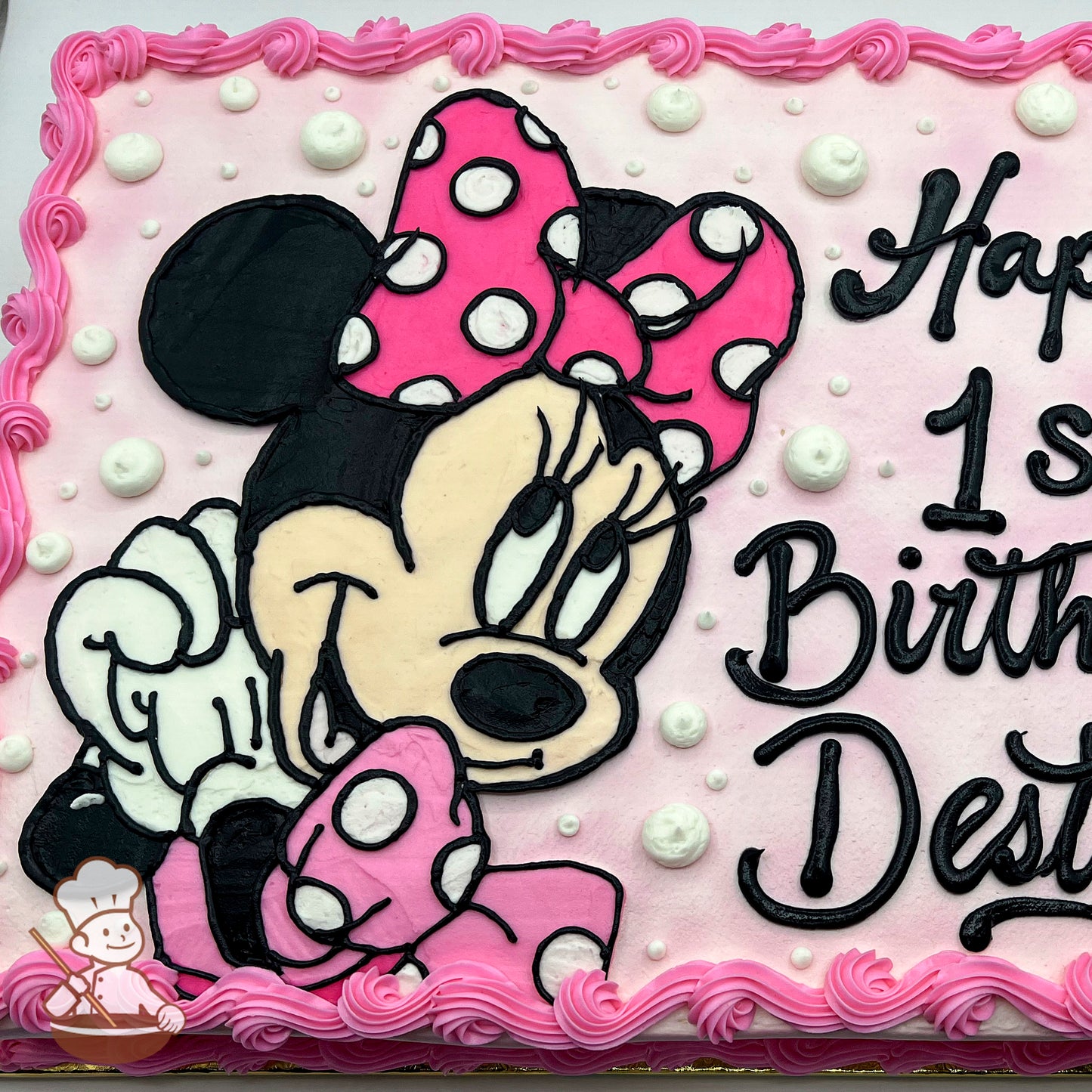 Pink sheet cake with a buttercream portrait of Minnie Mouse, featuring her pink polka-dot bow and dress. Pink swirled border and white dot accents.