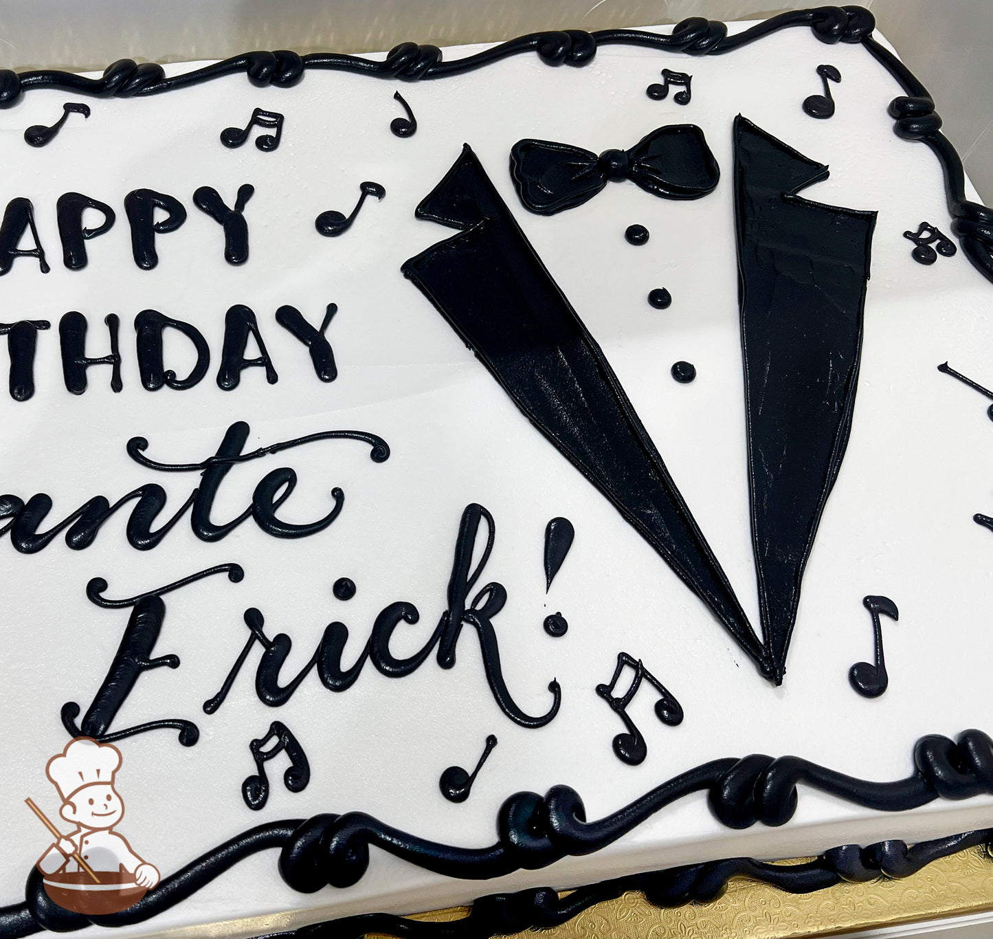 Sheet cake with white frosting, black tuxedo design, bow tie, buttons, and scattered music note decorations. Black piped border.