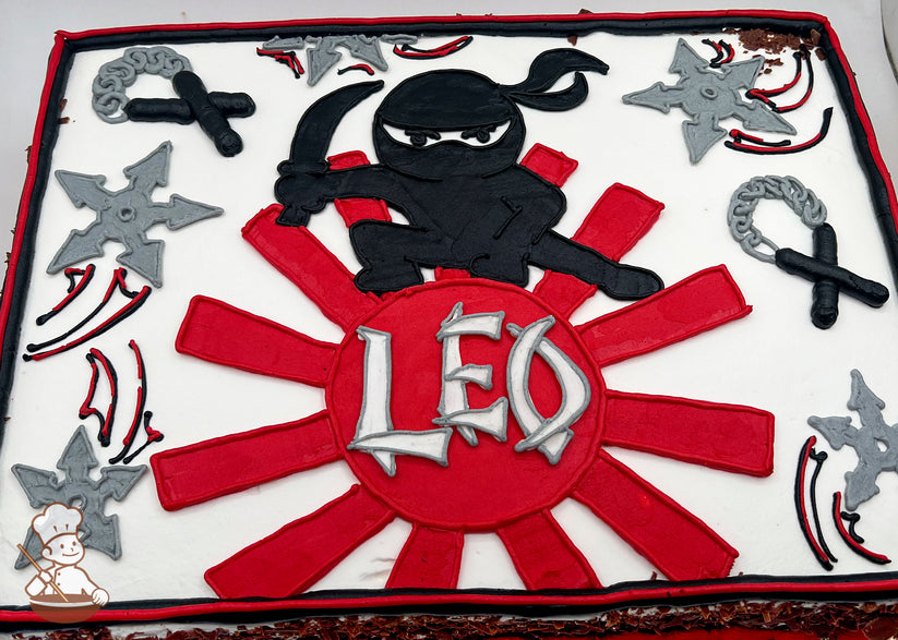 A sheet cake with buttercream decorations featuring a black ninja holding a sword, red sunburst design, gray shuriken's, and nun chucks.