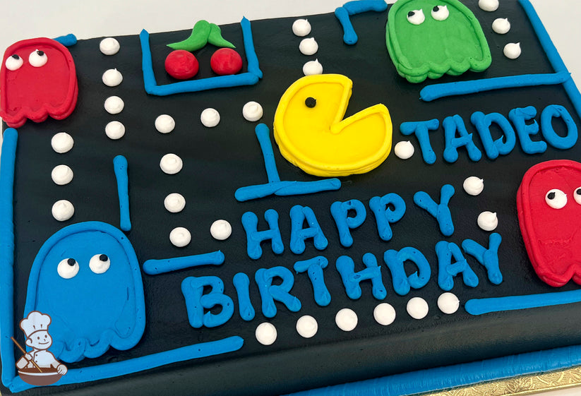 Black sheet cake decorated with a Pac-Man theme, featuring a yellow Pac-Man, colorful ghosts, white dots, blue maze lines, and red cherries.