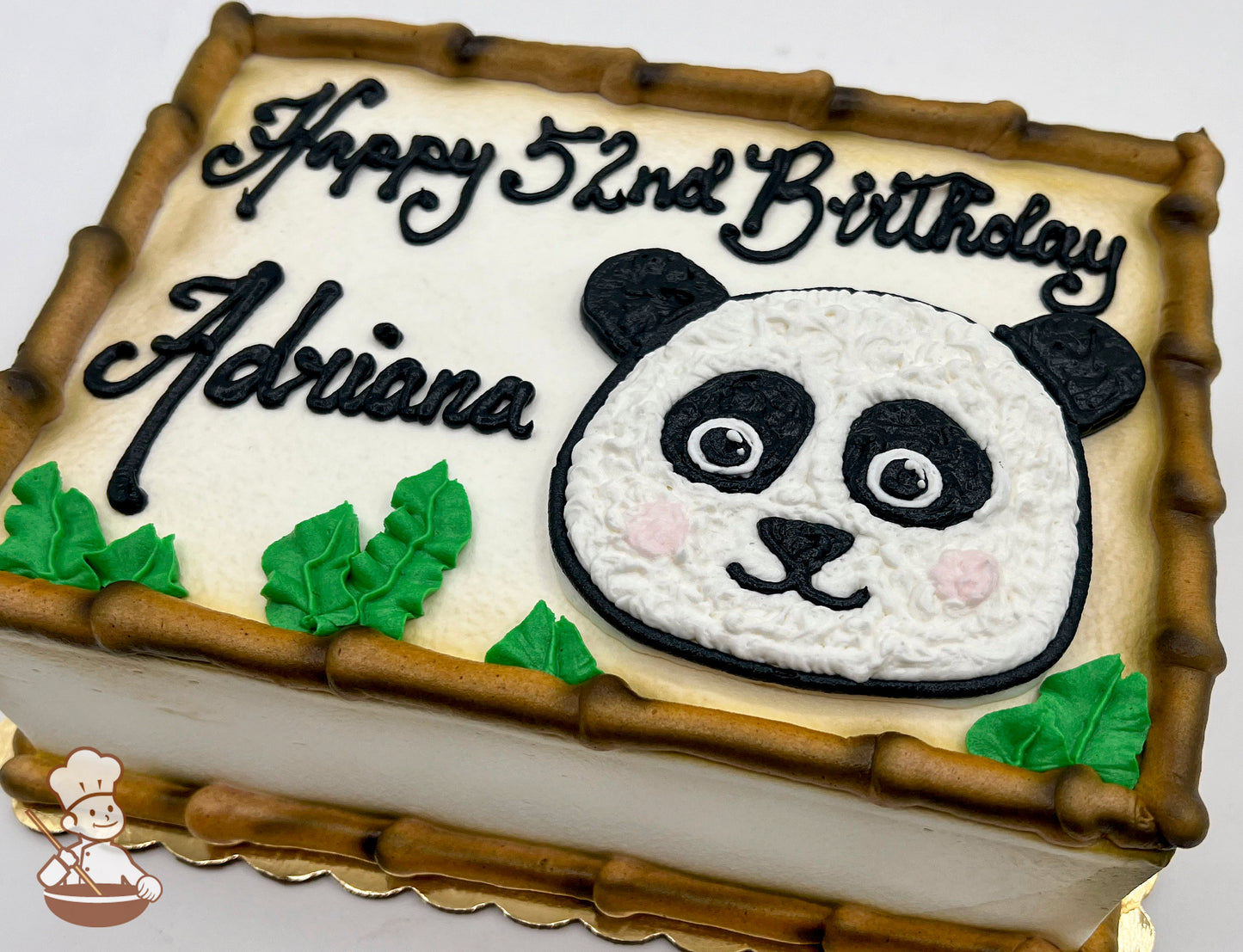 Sheet cake with buttercream panda face, bamboo border, and green leaves.