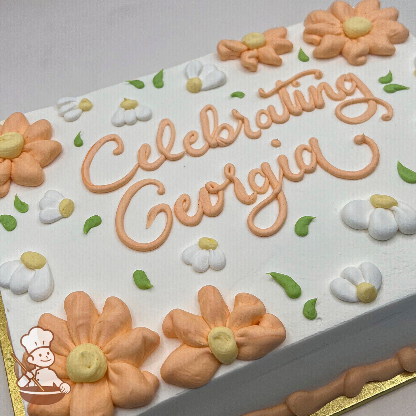 Sheet cake with peach and white buttercream daisies, green leaves, and peach piping.