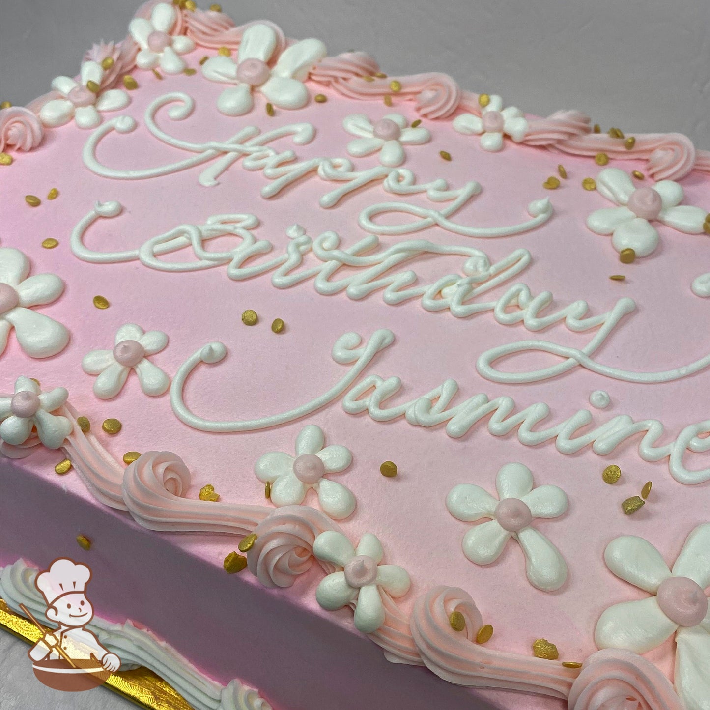 Pink sheet cake with buttercream daisies, pink swirls, and gold sprinkles.