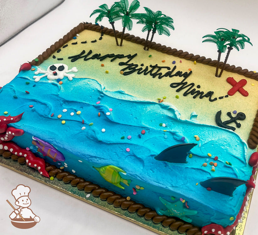 Sheet cake with buttercream decorations featuring a beach and ocean theme, with plastic palm trees, a red "X," an anchor, a skeleton head, plastic shark fins, fish, and a starfish. Rope trim borders the cake.